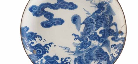 Plat en porcelaine hue blanche à décor bleu sous couverte de deux dragons évoluant parmi les nuages
